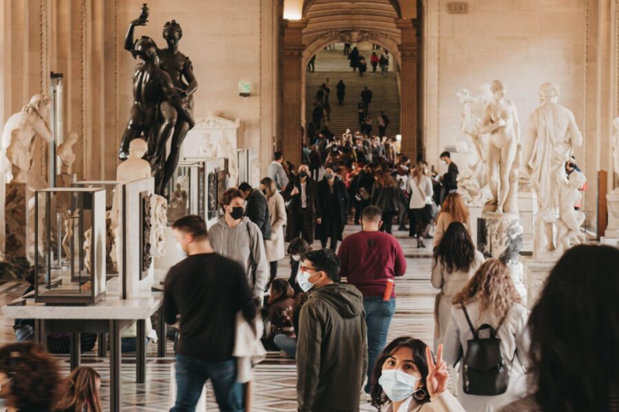 Visitors exploring and photographing exhibits inside a bright historic museum gallery