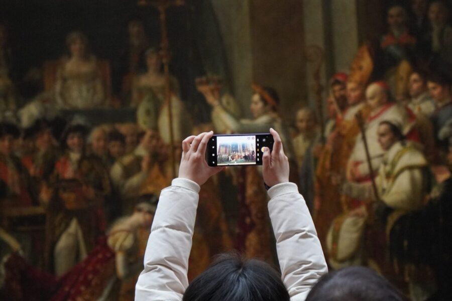 Visitors photographing historic artwork inside a museum gallery