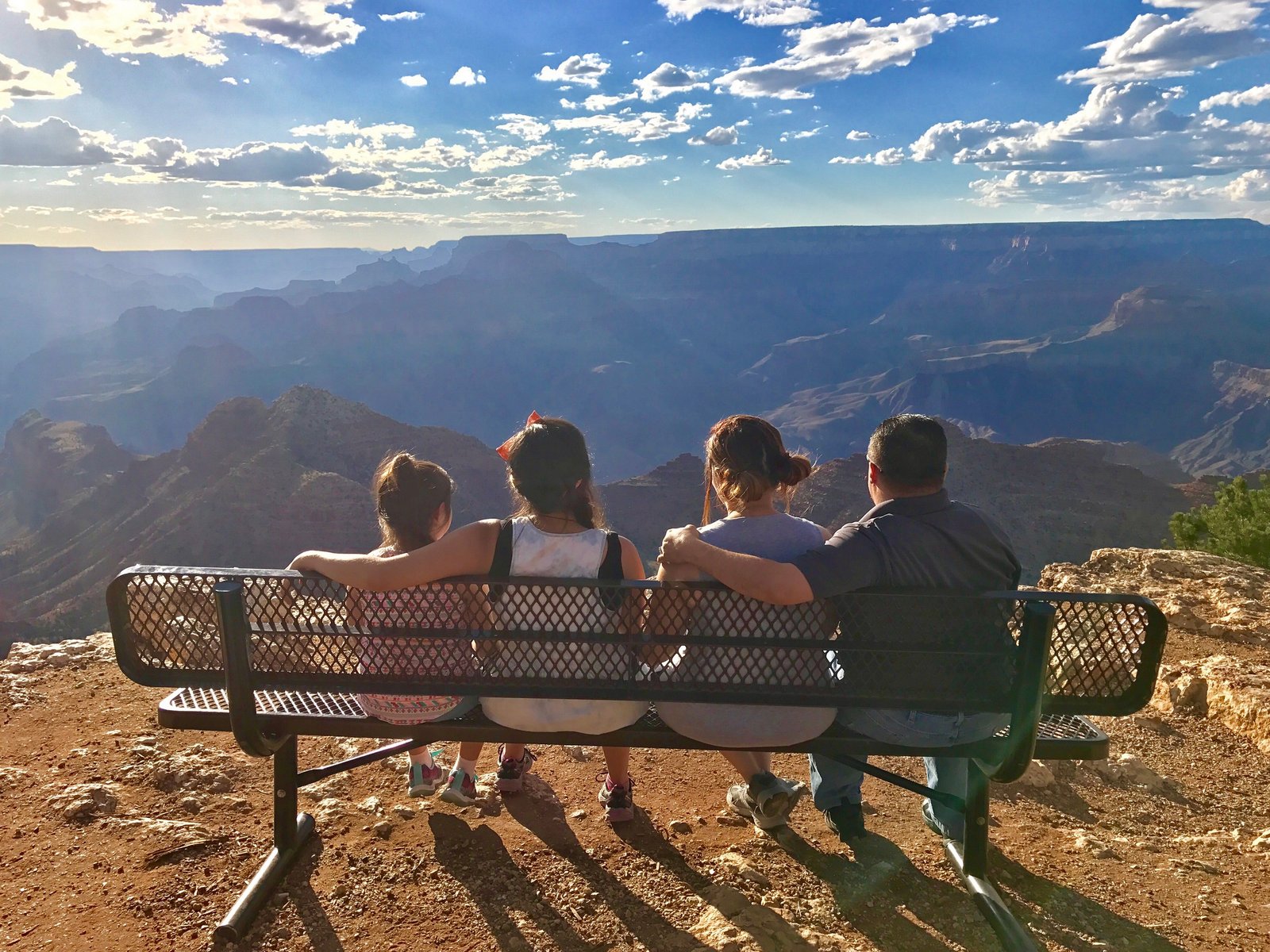 Family sitting on a bench at Desert View overlooking Grand Canyon