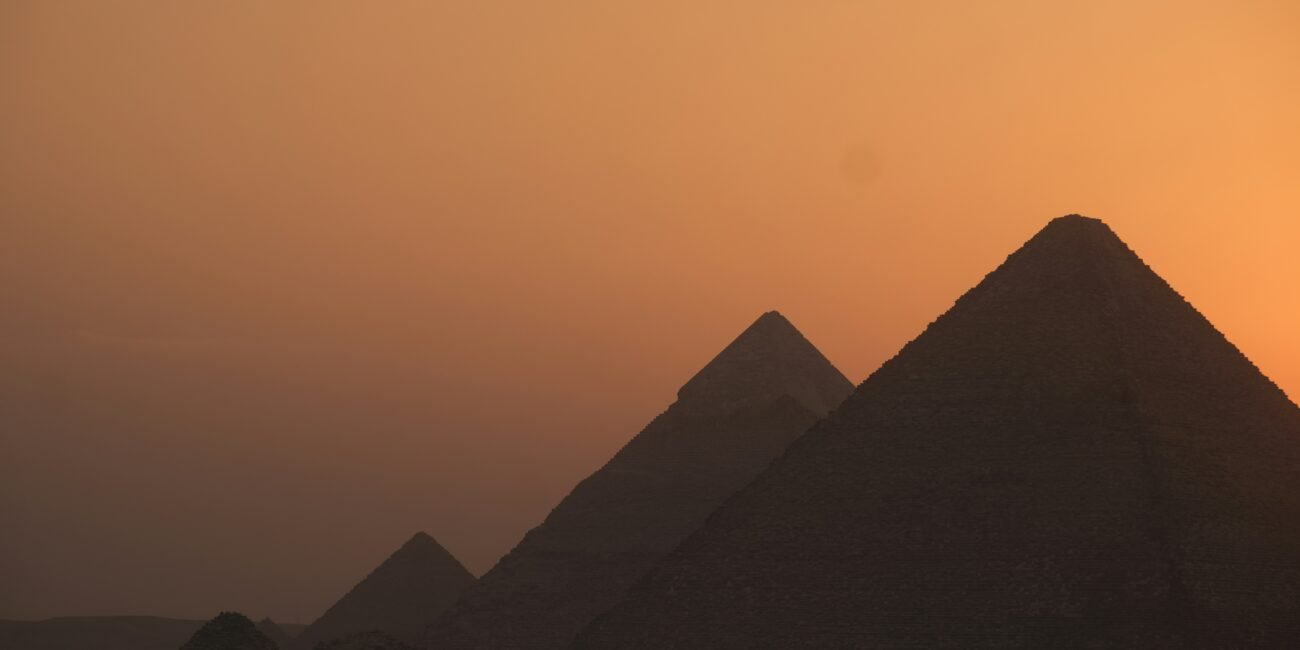 The pyramids of Giza silhouetted against a warm sunset sky in Egypt