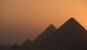 The pyramids of Giza silhouetted against a warm sunset sky in Egypt