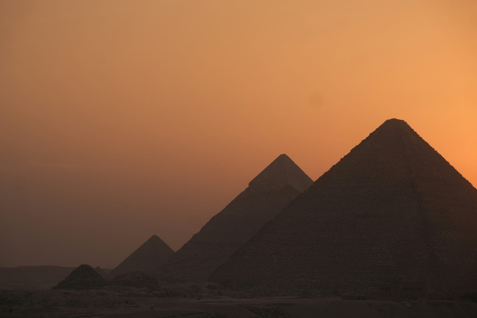 The pyramids of Giza silhouetted against a warm sunset sky in Egypt