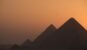 The pyramids of Giza silhouetted against a warm sunset sky in Egypt