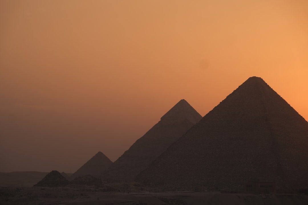The pyramids of Giza silhouetted against a warm sunset sky in Egypt