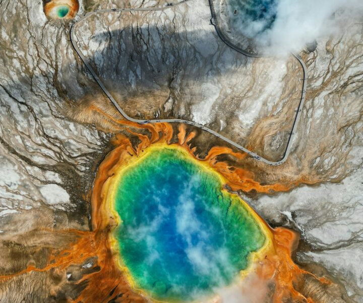 Aerial view of Grand Prismatic Spring showing vivid blue, turquoise, orange, and yellow geothermal colors in Yellowstone National Park