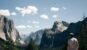 A traveler seen from behind looking out across Yosemite Valley and the surrounding mountains