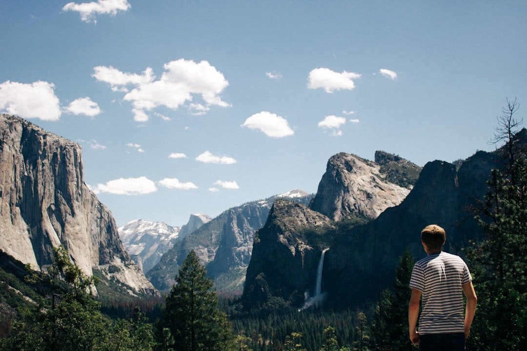 A traveler seen from behind looking out across Yosemite Valley and the surrounding mountains