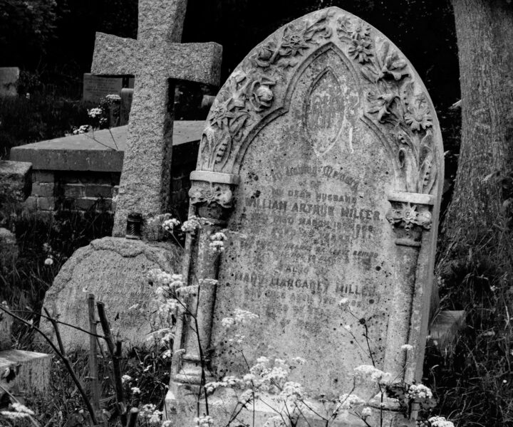 Weathered gravestones and a stone cross in a historic London churchyard