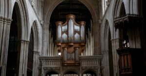 Historic English church interior with stone arches, timber ceiling, organ, and central aisle