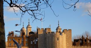 Tower of London fortress in warm evening light with birds flying in front