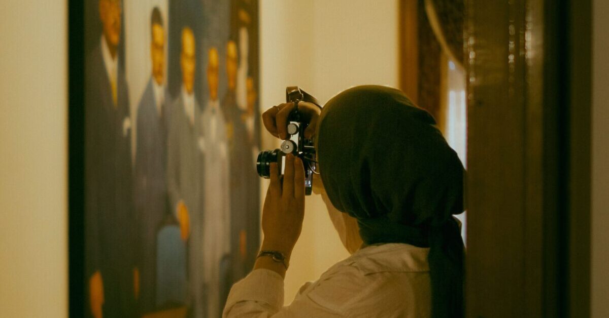 Museum visitor using a camera to photograph an artwork in a gallery