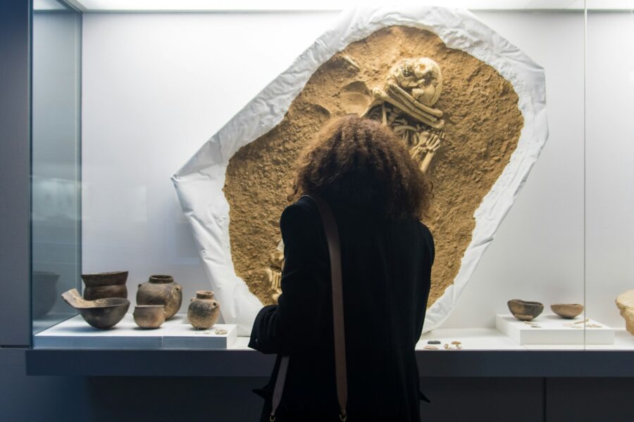 Visitor studying pottery and a prehistoric burial display in an archaeology museum