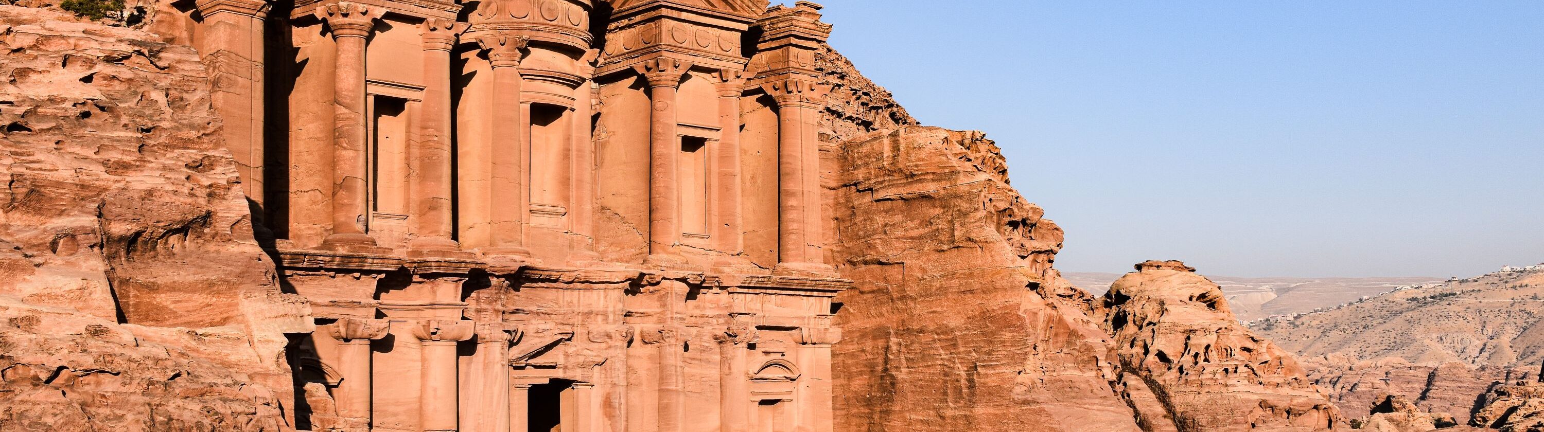 The Monastery at Petra carved into red sandstone beneath a clear blue sky in Jordan
