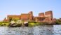 Ancient Philae Temple beside the Nile at Aswan with stone columns, river water, and desert hills