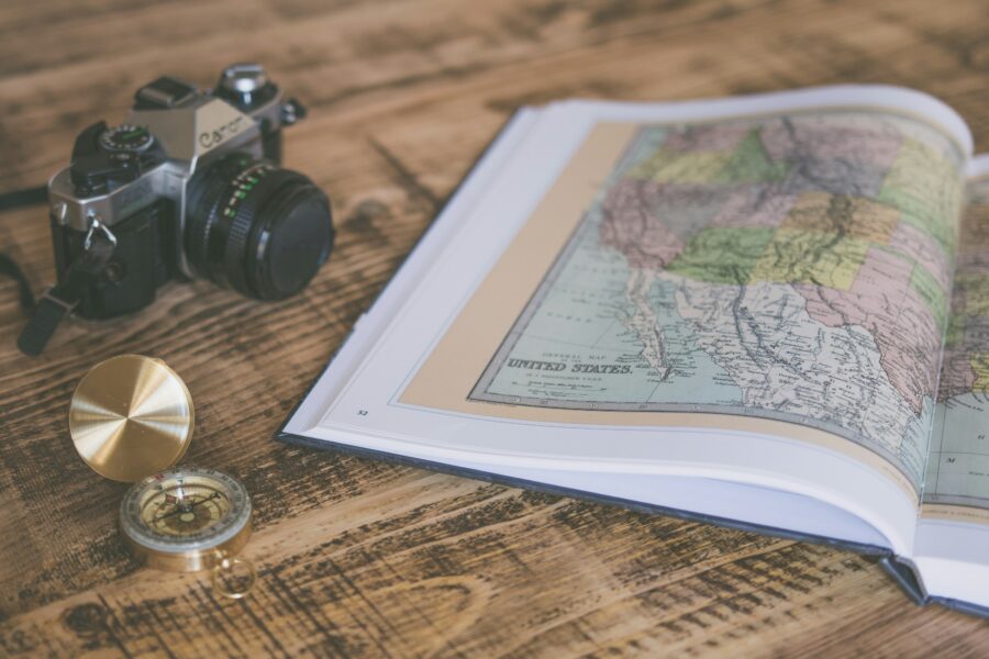 Compass resting on a map beside travel gear, suggesting navigation and worldwide exploration