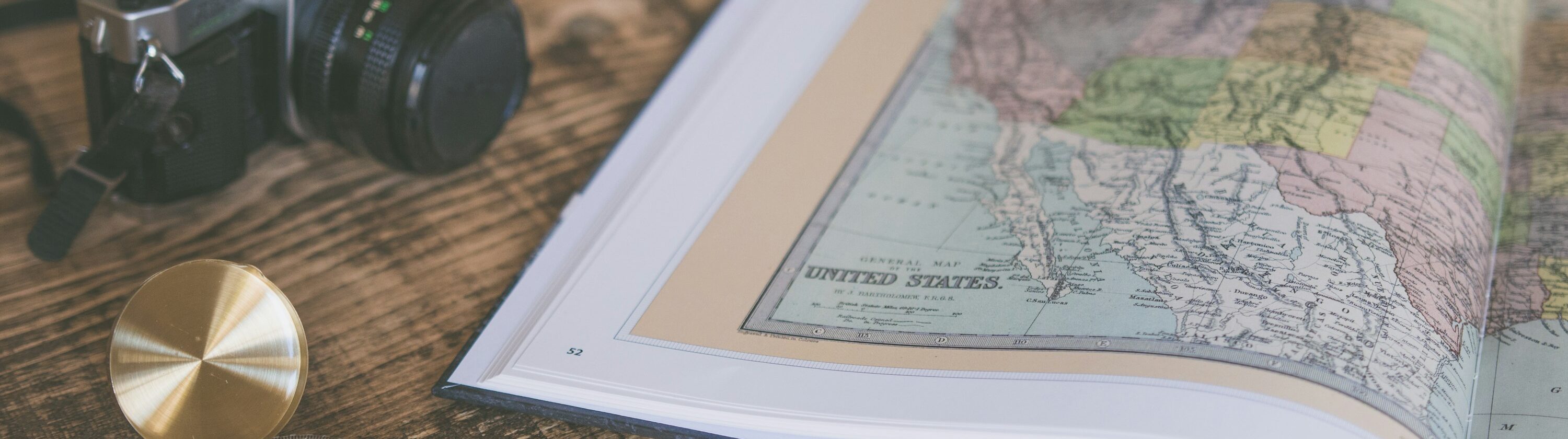 Compass resting on a map beside travel gear, suggesting navigation and worldwide exploration